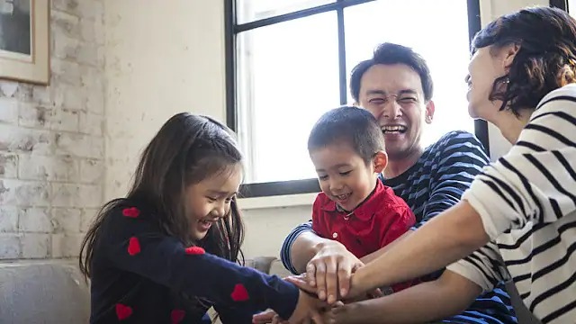 Família de três pessoas feliz jogando um jogo de tabuleiro em casa