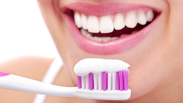 Sorriso branco feminino e uma escova de dente com creme dental remineralizante