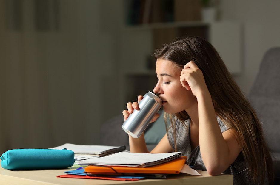 adolescente estudando e bebendo bebida energética