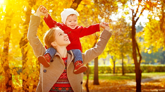 Mãe passeando com seu filho bebê nos seus ombros em um parque