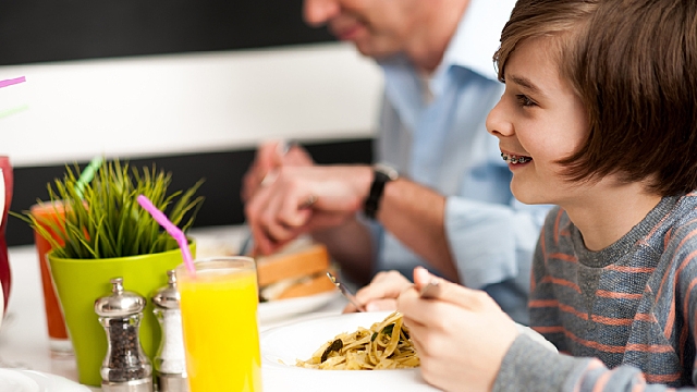 Criança com aparelhos ortodônticos comendo em família