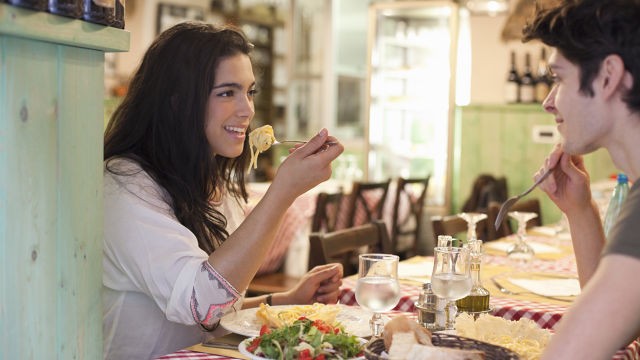 mulher sorrindo e comendo com seu amigo