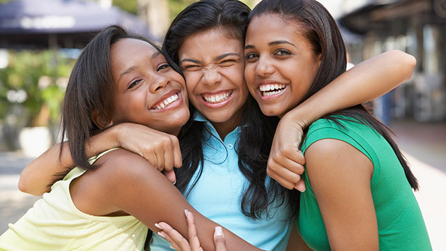 Três adolescentes abraçadas e sorrindo