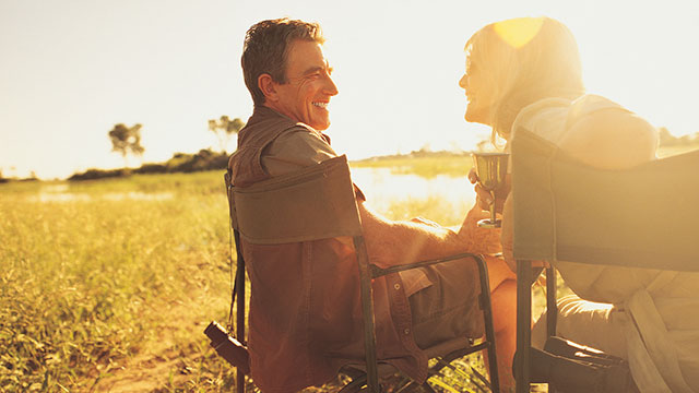 An elderly couple is lounging in the field