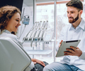 Dentista mostrando um tablet para uma paciente no consultório odontológico