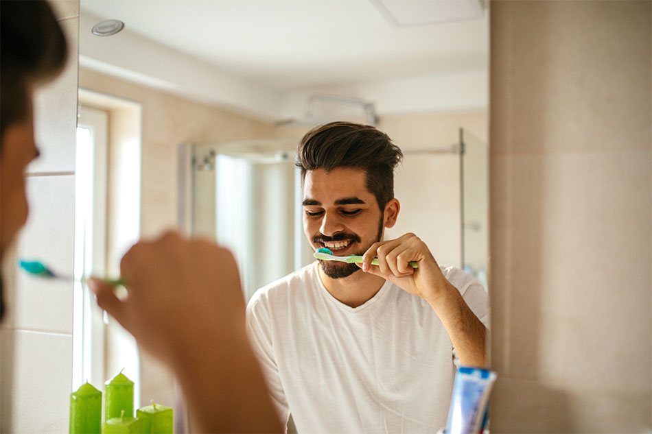 O jovem está escovando os dentes