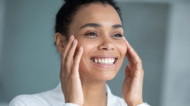 Mulher sorrindo para o espelho após usar a sua escova interdental