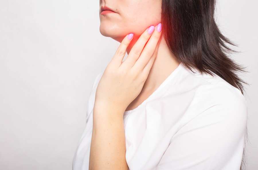 Moça colocando a mão na glândula submandibular inchada