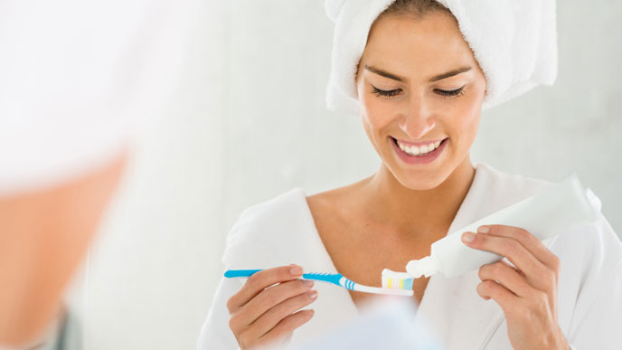 Mulher feliz no banheiro escovando os dentes