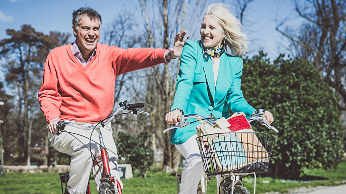 Casal montando bicicleta e sorrindo no parque