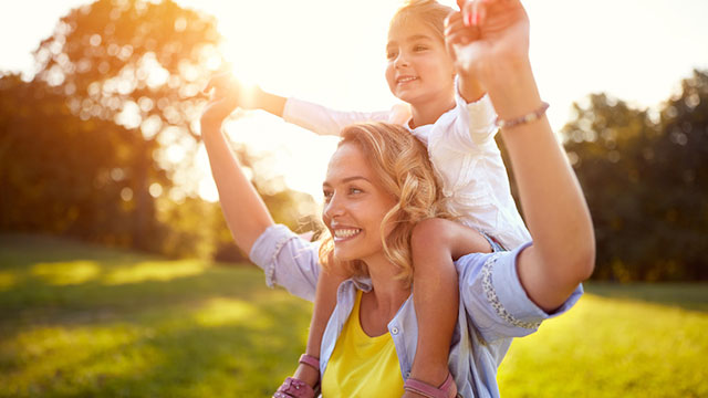 Mãe e filha sorrindo aproveitando o sol