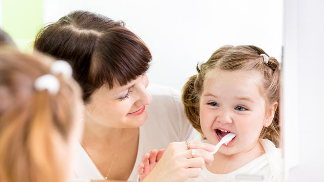 Mãe Ajudando A Filha A Escovar Os Dentes