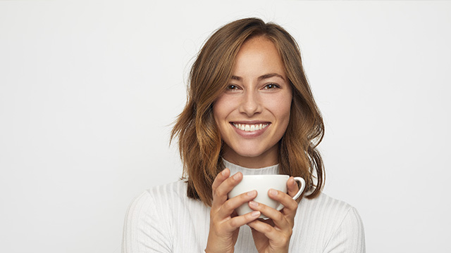 imagem de uma jovem feliz com uma xícara de café