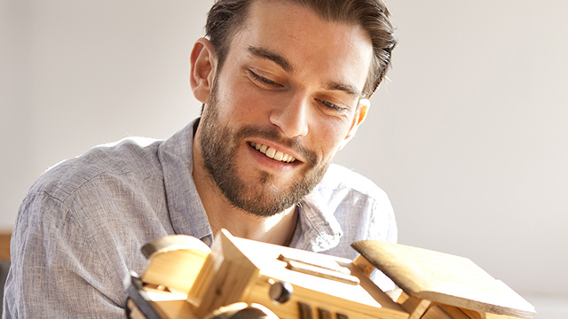 a man admiring a wooden car toy