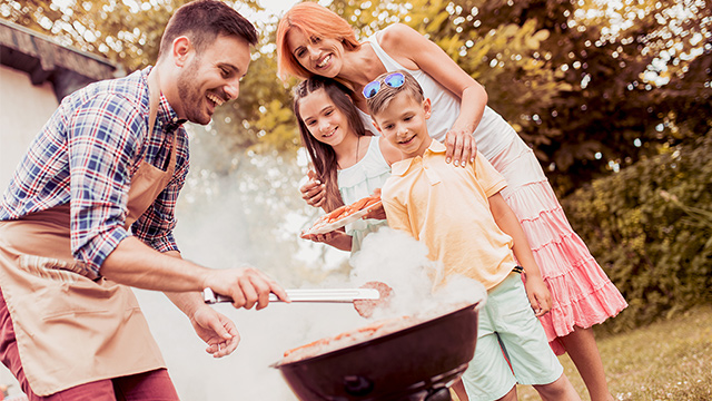 family making dinner on a grill